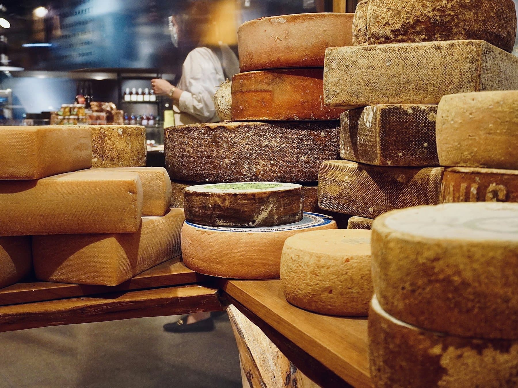 Aged cheese wheels stacked in an artisan cheese shop